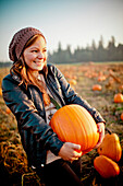 Portrait of a woman holding a pumpkin.