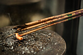 Lighting incense sticks from a small flame at a temple in Hong Kong.