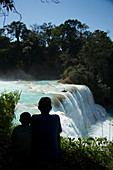 A pair of local villager boys look on as a kayaker drops off a waterfall on the Rio Tulija, also known as Agua Azul in Chiapas, Mexico.