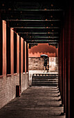 A tourist walking through a corridor in the Forbidden City in Beijing, China
