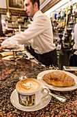 The typical Milanese breakfast with cappuccino and homemade brioche at the old Cafe Cova, icon of Milan, Lombardy, Italy, Europe