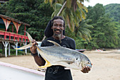 A man holds up a freshly caught Trevally fish at Castara in Tobago, Trinidad and Tobago, West Indies, Caribbean, Central America