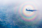 Aerial view of the shadow of a commercial airline in the middle of a sundog over a cloudy North Slope tundra, North Slope, Alaska, United States of America