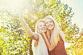 Two sisters having fun outdoors in a city park in autumn and taking selfies of themselves, Edmonton, Alberta, Canada