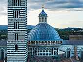 Striped facade of a tower and dome roof of Siena Cathedral, Siena, Italy
