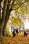Kinder spielen im Herbstlaub auf dem Christenberg, im Hintergrund das ehemalige Küsterhaus (Fachwerk) auf dem Christenberg, Münchhausen, Burgwald-Ederbergland, Nordhessen, Hessen, Deutschland, Europa