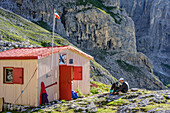 Mann sitzt vor Biwak Minuzio, Cima la Fradusta, Val Canali, Pala, Dolomiten, UNESCO Weltnaturerbe Dolomiten, Trentino, Italien