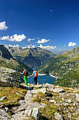 Man and woman hiking, barrier lake Zillergrund in background, hut Plauener Huette, Reichenspitze group, Zillertal Alps, Tyrol, Austria