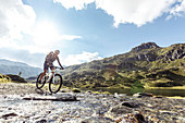 Mountainbikerin spritzt durch Gebirgsbach am Giglachsee, Niedere Tauern, Steiermark, Österreich