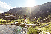 Mountainbiker crossing Giglach Creek, Lower Tauern Mountains, Steiermark, Austria