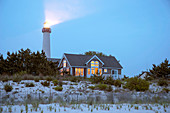 Lighthouse beaming near beach house