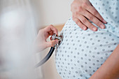 Doctor listening to belly of pregnant woman