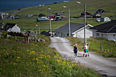 Zwei kleine Mädchen laufen zu ihrem Dorf, Färöer Inseln