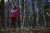 Young female runner stretching her leg in a forest, Fuessen, Bavaria, Germany