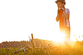 girl putting on her bicyle helmet on a meadow, Fuessen, Bavaria, Germany