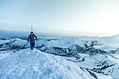 Junger Skifahrer steigt durch den Tiefschnee auf den Gipfel eines Berges, Gudauri, Mzcheta-Mtianeti, Georgien
