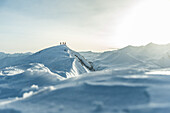 Three young skiers hikiing up through the deep powder snow to a mountain peak, Gudauri, Mtskheta-Mtianeti, Georgia