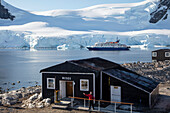 Museum and shop of Gonzalez Videla Antarctic Base (Chile) with expedition cruise ship MV Sea Spirit (Poseidon Expeditions) behind Waterboat Point, near Paradise Harbor (Paradise Bay), Graham Land, Antarctic Peninsula, Antarctica
