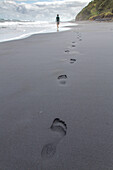 Fußspur, Sandstrand, schwarzes Sand, barfuss, Mensch im Hintergrund, Hochformat, Westküste der Nordinsel, Neuseeland