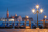 Blick vom Markusplatz mit Gondeln und Laternen zur Insel San Giorgio Maggiore mit ihrer gleichnamigen Kirche im Blau der Nacht, San Marco, Venedig, Venezien, Italien
