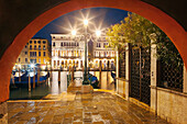 Blick über den Canal Grande mit den beleuchteten Fassaden des Palazzo Ca' Loredan und des Palazzo Ca' Farsetti (von links) im Blau der Nacht und Gondeln im Vordergrund, San Marco, Venedig, Venezien, Italien