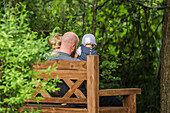 Father and two children sitting on a bench in the garden, Holiday, Vacation, Summer, Spreewald, Oberspreewald, Brandenburg, Germany