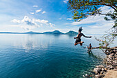 Man jumping in the bay of Rabaul with Volcano Tavurvur in the background, East New Britain, Papua New Guinea, Pacific
