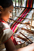 Ein kleines Mädchen lernt die Kunst des Webens auf einer Hand Webstuhl, Chittangong Hill Tracts Region, Bangladesch, Asien