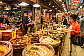 Shopper with basket considers purchase at local Japanese food stall, Nishiki Market (Kyoto's Kitchen), Downtown Kyoto, Japan, Asia