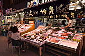 Diners sitzen und sprechen mit Meeresfrüchten Stall Besitzer, Omicho frischen Lebensmittel-Markt, Netzwerk von überdachten Stall gesäumten Straßen, Kanazawa, Japan, Asien