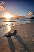 Der karibische Sonnenuntergang umrahmt die Überreste von Baumstämmen auf Ffryes Beach, Antigua, Antigua und Barbuda, Leeward Islands, Westindische Inseln, Karibik, Mittelamerika