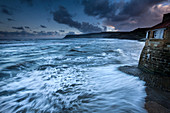 Nordsee-Wellen, die über gepflasterte Slipway bei Sonnenuntergang in Robin Hoods Bay, North Yorkshire, Yorkshire, England, Großbritannien, Europa zusammenstoßen
