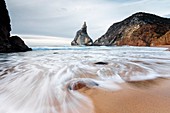 Ocean waves crashing on the sandy beach of Praia da Ursa surrounded by cliffs Cabo da Roca Colares Sintra Portugal Europe.
