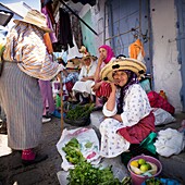 Moroccan women in traditional clothing selling vegetables in street market. Chaouen, Moroco