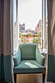 Chair in a window with cityscape behind in Rome, Italy.