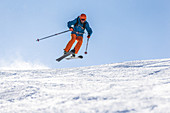 Junger Skifahrer springt über eine Piste, Kaprun, Salzburg, Österreich