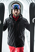 Young male skier standing with his skis in a tunnel for persons, Kaprun, Salzburg, Austria