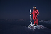 Junger Skifahrer steht auf dem Gipfel eines Berges über den Wolken bei Nacht, Kaprun, Salzburg, Österreich