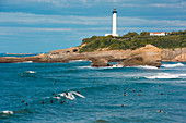 Surfer reiten auf Wellen vor Leuchtturm, Saint-Jean-de-Luz, Pyrénées-Atlantiques, Frankreich, Europa