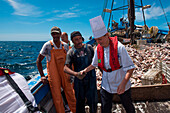 Executive Chef Yvonne Happe of expedition cruise ship MS Bremen (Hapag-Lloyd Cruises) purchases fresh fish from fishermen aboard fishing boat Costa Neves - CN in the middle of the ocean