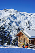 Frau und Mann auf Skitour sitzen an Almhütte und machen Pause, Tuxer Alpen, Tirol, Österreich