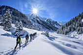 Several persons backcountry skiing ascending through valley Frommgrund, Frommgrund, Kitzbuehel Alps, Tyrol, Austria