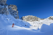Frau auf Skitour steigt zur Sella Nabois auf, Jof Fuart und Sella Nabois im Hintergrund, Julische Alpen, Friaul, Italien
