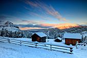 The sunrise lights up the snowy woods and huts, Passo Delle Erbe, Funes Valley, South Tyrol, Italy, Europe