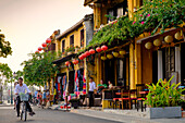 Young couple riding a bicycle past attractive cafe shop houses in Hoi An, Vietnam, Indochina, Southeast Asia, Asia