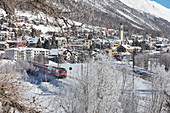 The red train runs across the snowy landscape around Samedan, Maloja, Canton of Graubunden, Engadine, Switzerland, Europe