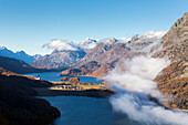 View of Sils and the blue lake surrounded by mist in autumn, Surlej, St. Moritz, Canton of Graubunden, Engadine, Switzerland, Europe