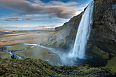 Photographer taking pictures of Seljalandsfoss waterfall, Porsmerkurvegur, Sudurland, Iceland, Europe