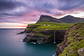 Gasadalur, Vagar island, Faroe Islands, Denmark, The iconic waterfall jumping from the cliff into the ocean at sunset