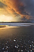 Po river park, Piedmont, Italy, Rocky beach on Po river banks, with stormy clouds coloured by the sunset lights